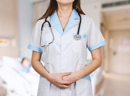 an image of a woman wearing a white button up hospital uniform with light blue trim and a stethoscope draped around her neck